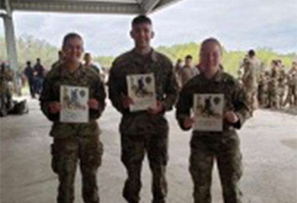 三名ROTC学生微笑着展示他们的挪威徒步行军徽章证书
