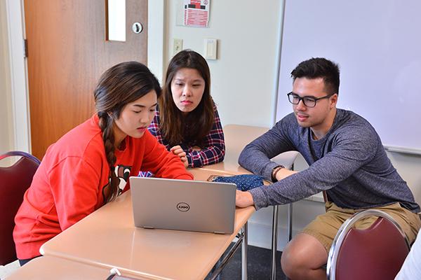 three students gather around a computer