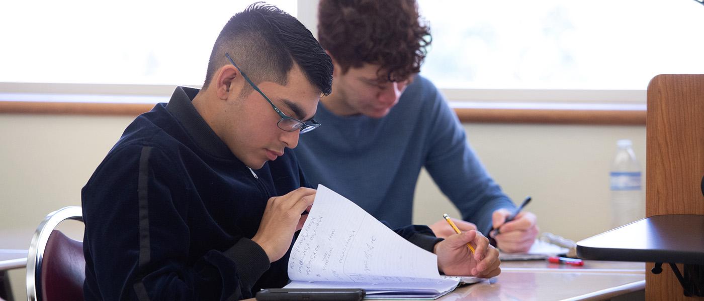 Close up of two male students taking notes during math class
